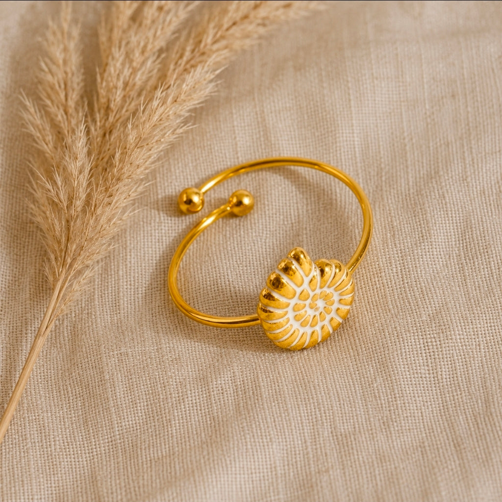 Verstellbarer Nautilus-Muschelring aus goldfarbenem 304 Edelstahl mit weißer Emaille auf Leinenstoff mit Pampasgras